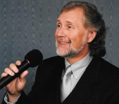 A man in a suit and tie holding a microphone.