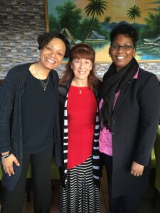 Three women standing next to each other in front of a painting.