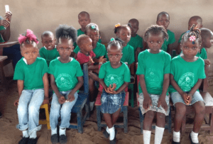 A group of children wearing green shirts and white socks.