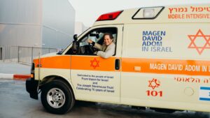 A woman driving an ambulance with the words " magen david adom in israel ".