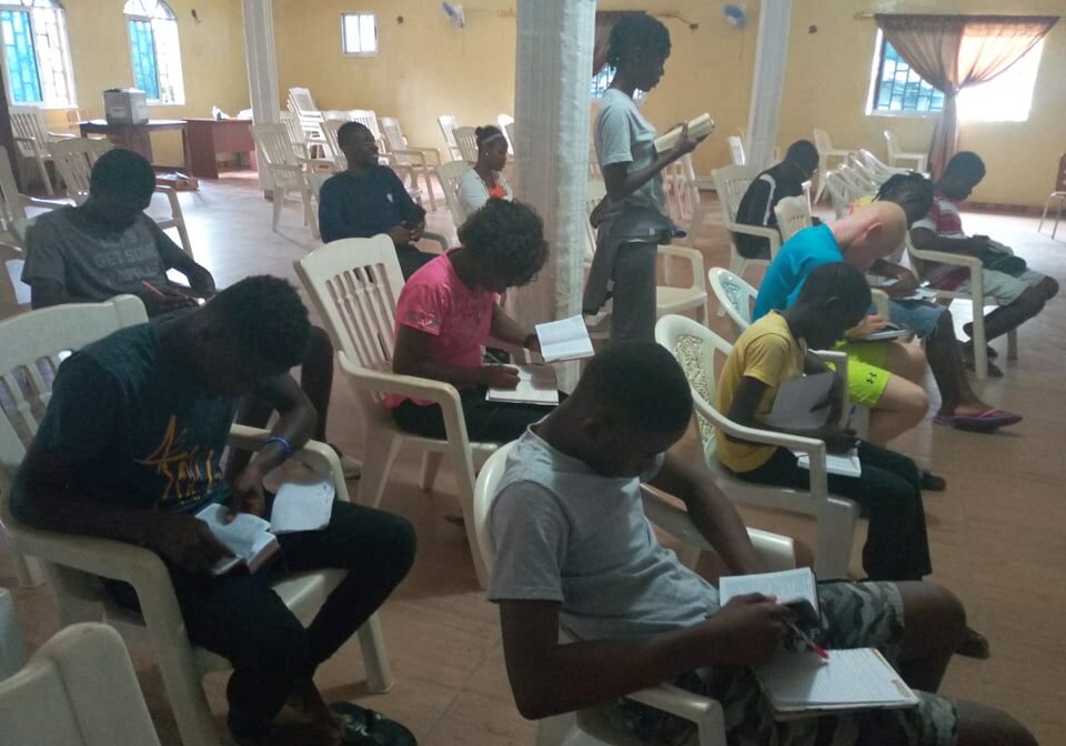 A group of people sitting in chairs reading books.