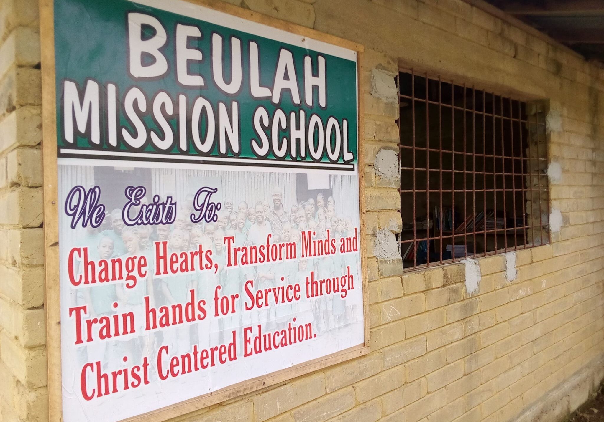 A sign on the side of a building that says " beulah mission school ".