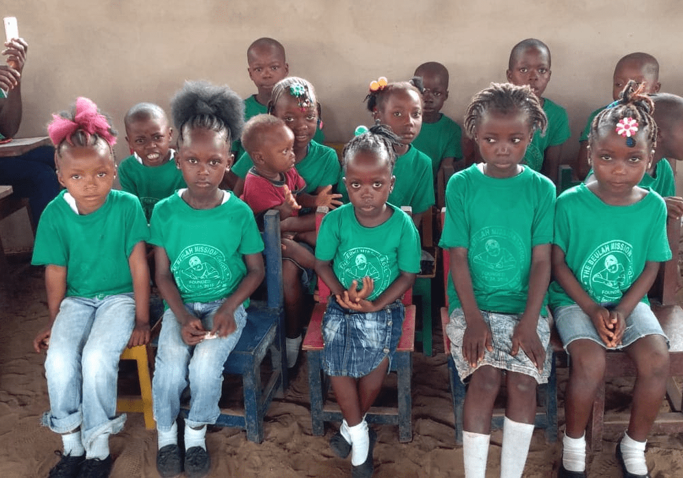 A group of children wearing green shirts and white socks.