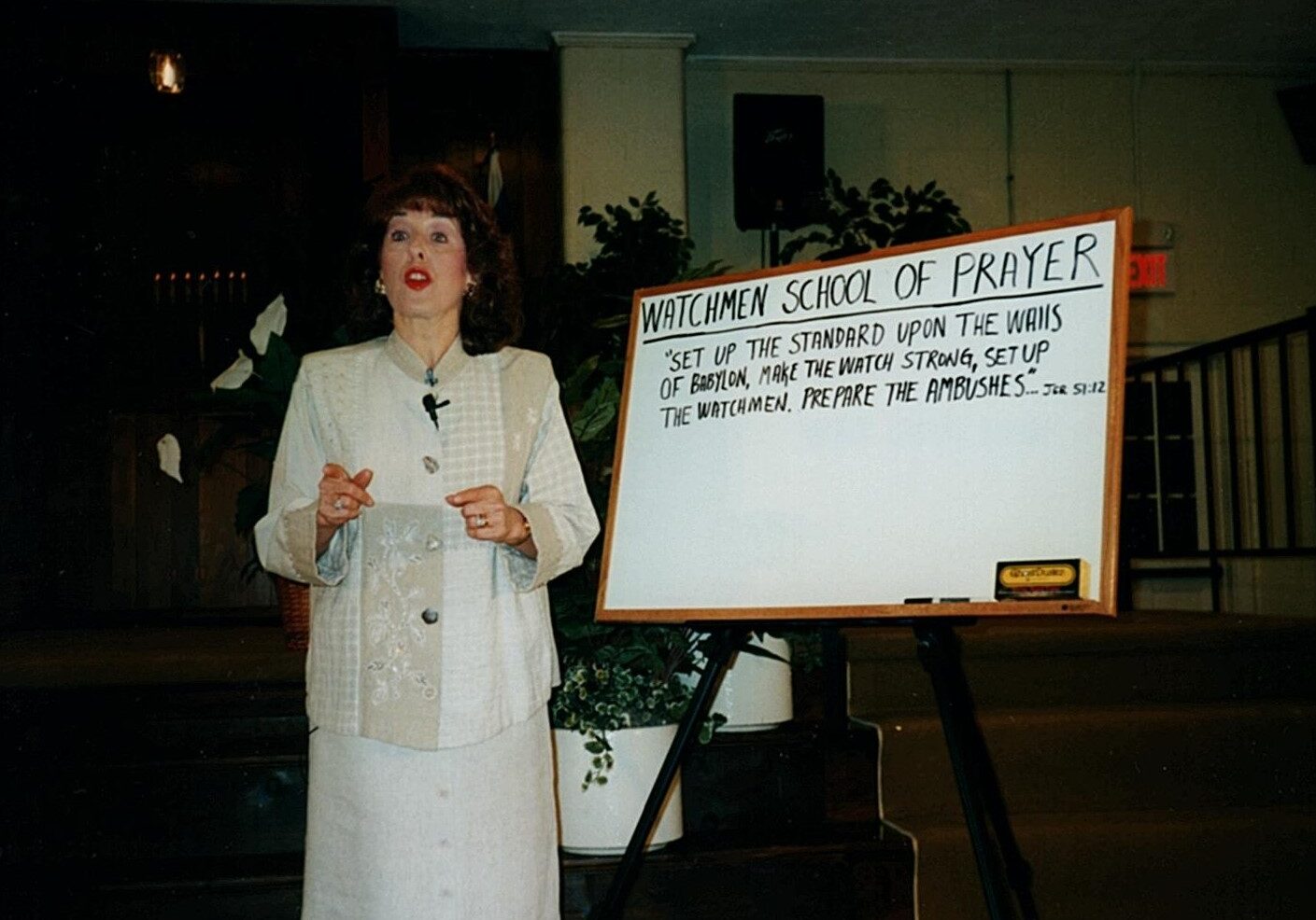 A woman standing in front of a sign.